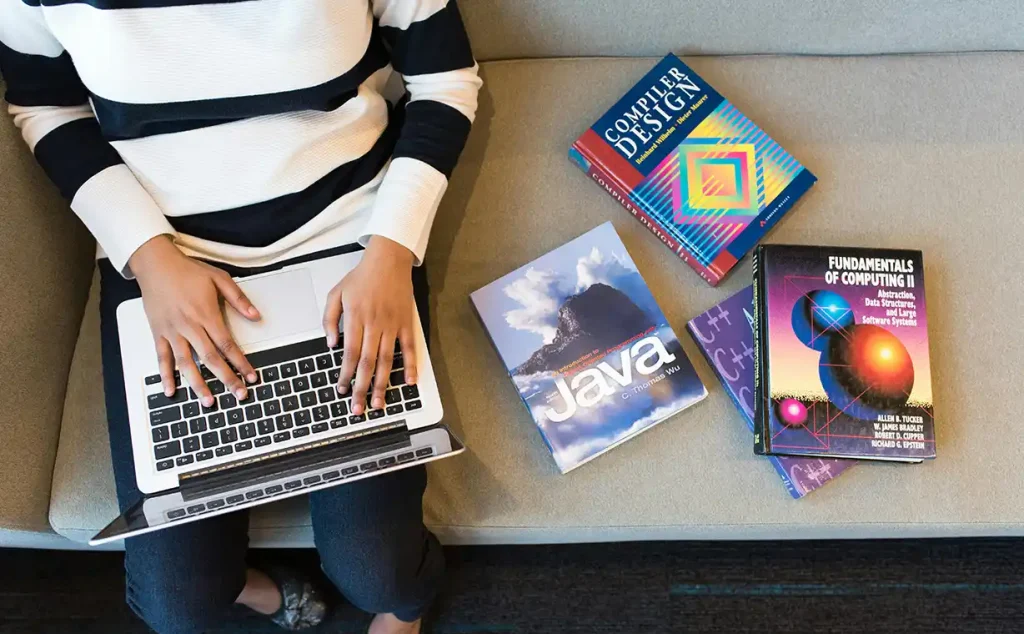 mujer sentada en sofa con libros de programación